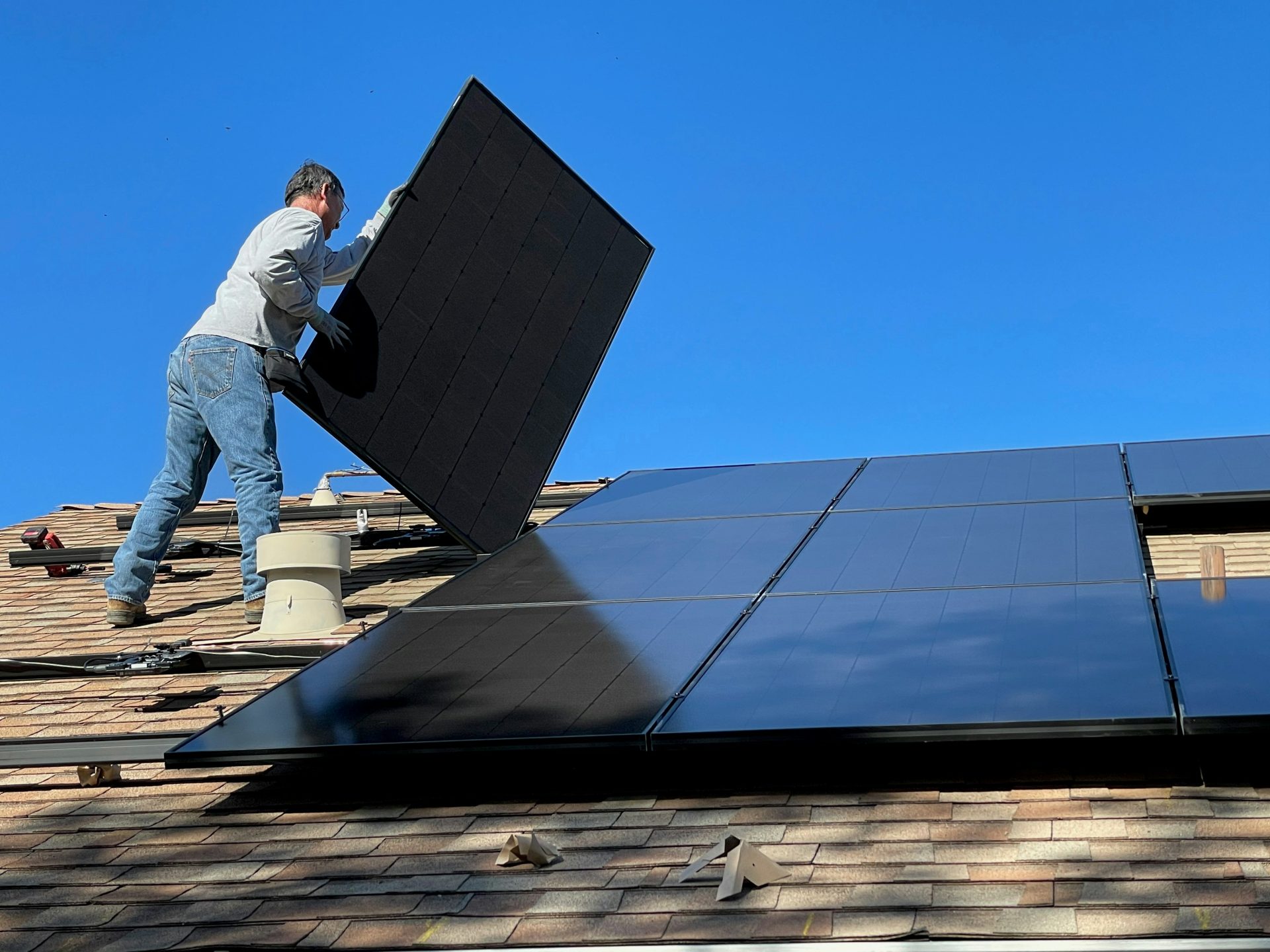 Mann in weißem Hemd und blauer Jeans sitzt auf einem weiß-schwarzen Solarpanel